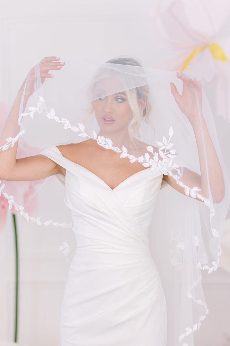 The fitted bodice of Misha crepe fitted wedding dress with a veil