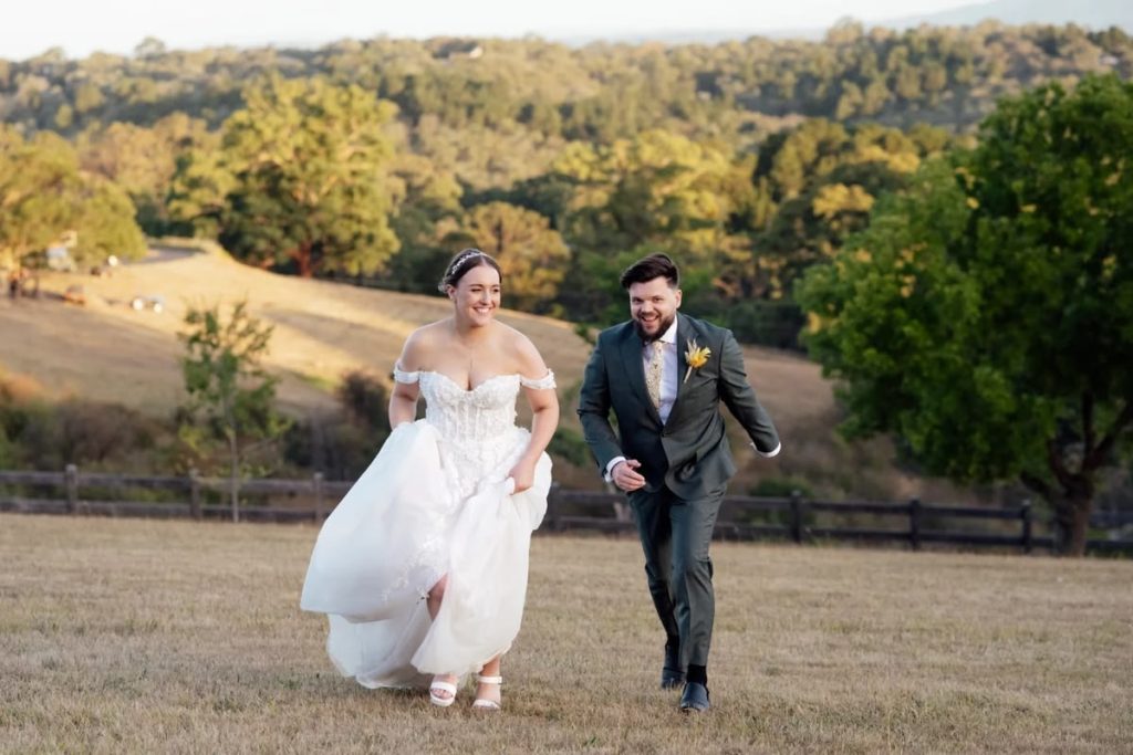 Real weddings at Leah S Designs, bride running in field wearing Trinity wedding dress.