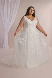 Full-length view of a model wearing a plus size A-line wedding dress with a flowing skirt.