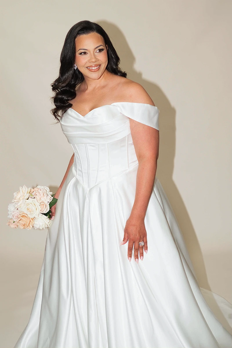 Close-up of a model wearing a plus size lace wedding dress with an off-the-shoulder neckline.