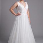 Size 22 model wearing a white plus size deb dress with a V-neck lace bodice and full tulle skirt